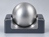 Conceptual CGI: low-inertia mechanical indexing assembly cutaway with one solid aluminium sphere gently retained against a dry precision locating groove; no liquid, no flotation