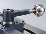 Conceptual CGI: A polished silver sphere screwed onto a short threaded rod at the end of a small industrial adjustment lever, threaded connection shown in restrained partial section, simple credible ergonomic handle assembly