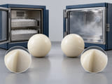 Conceptual CGI: Two ivory polymer spheres with dry conditioning container on one side and humid conditioning chamber on the other; engineering conditioning concept, no visible water inside solid balls