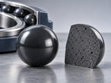 Conceptual CGI: Polished dense dark SiC sphere beside a conceptual dark ceramic material cross-section coupon showing a small distribution of pores; distinguish dense finished surface from internal quality review, no false microscopic scale