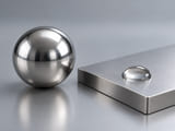 Conceptual CGI: Complete stainless sphere beside a flat stainless coupon and water droplet; surface and environment review concept