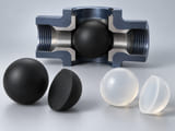 Conceptual CGI: One complete matte black rubber sphere beside its clean cut hemispherical section with uniform solid black elastomer throughout and no metal core; a second translucent silicone material concept at side